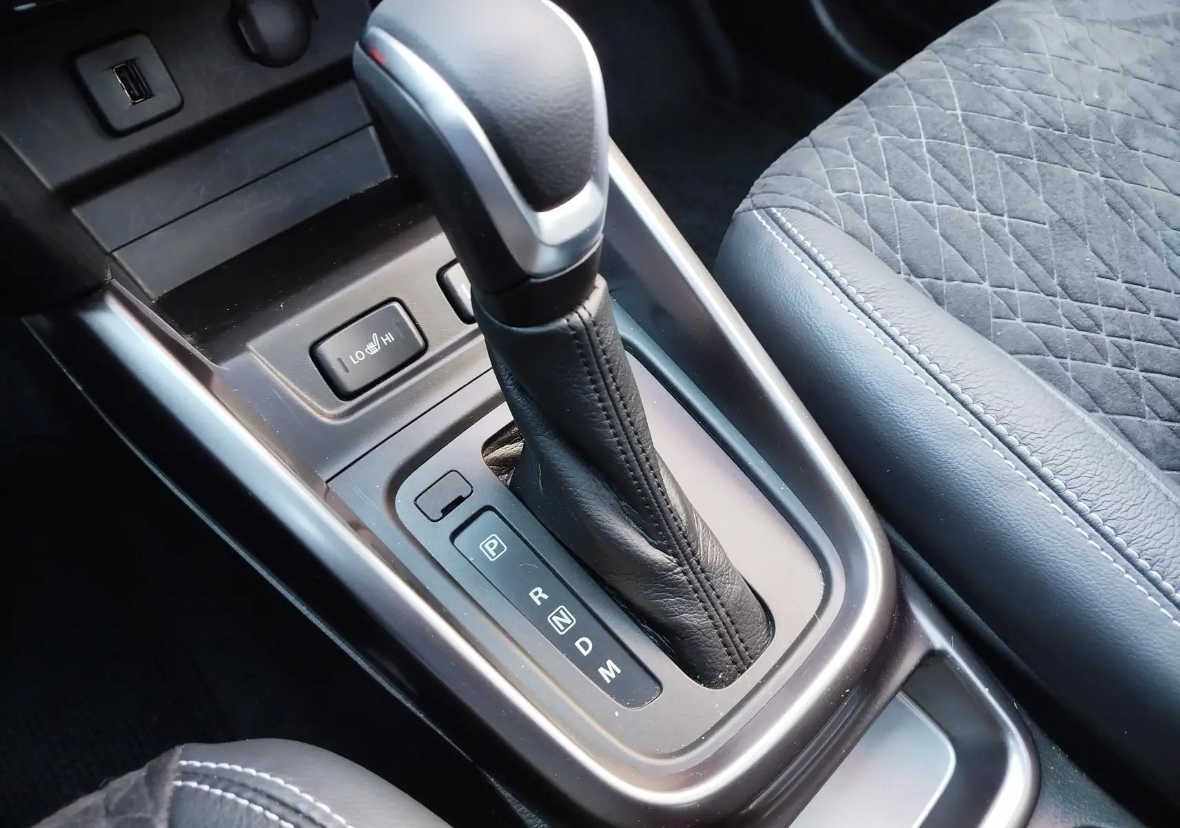 Gros plan sur la console centrale et levier de vitesse automatique du Suzuki Vitara 2023, intérieur gris avec surpiqûres blanches.