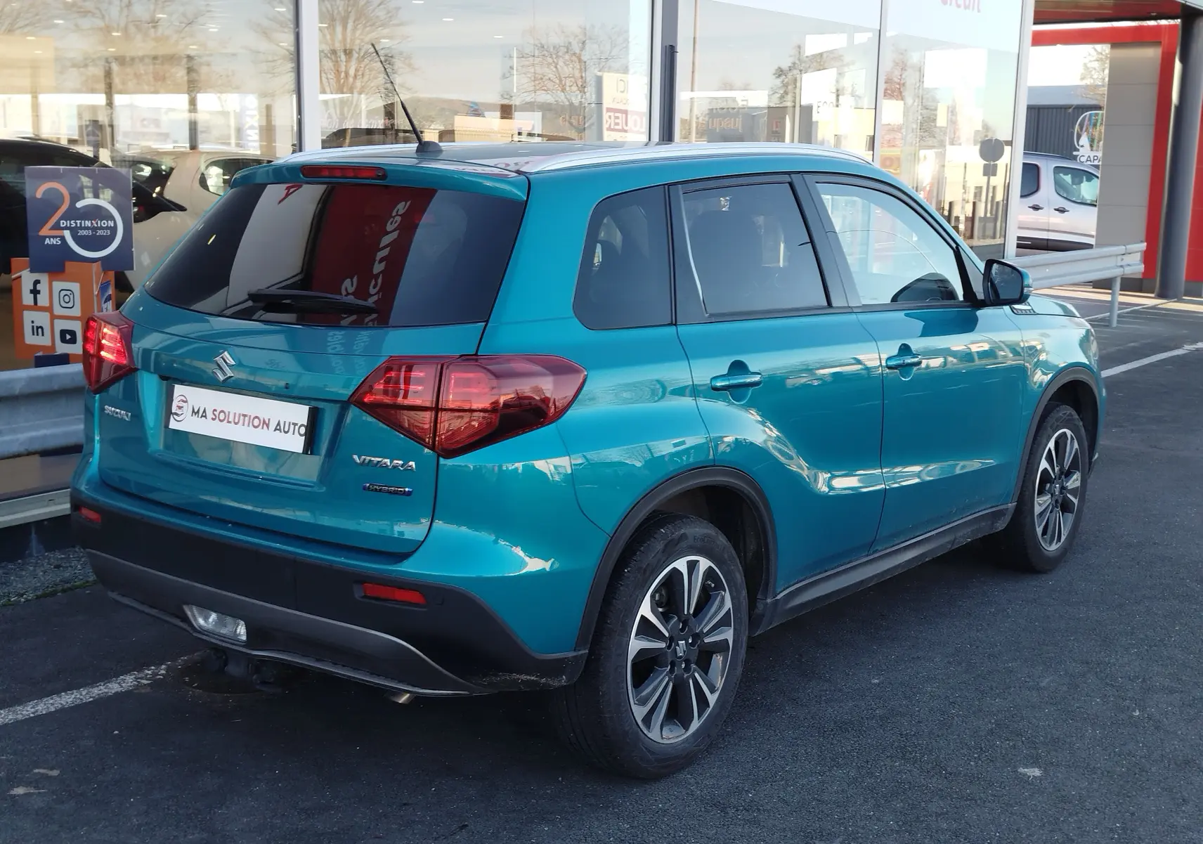 Vue 3/4 arrière droite du Suzuki Vitara 2023 en turquoise métallisé, avec vitres teintées et jantes bi-ton.