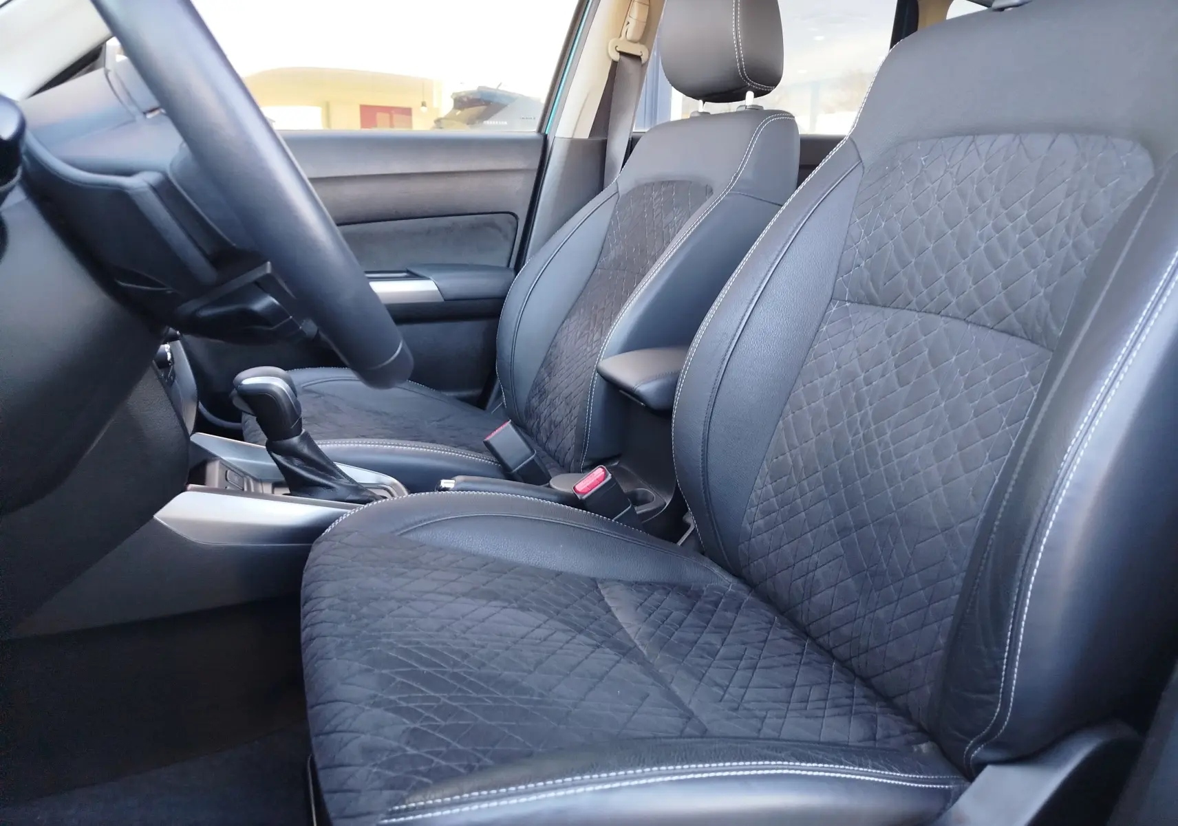 Vue intérieure côté gauche du Suzuki Vitara 2023, montrant les sièges avant en cuir et alcantara noir avec surpiqûres blanches.