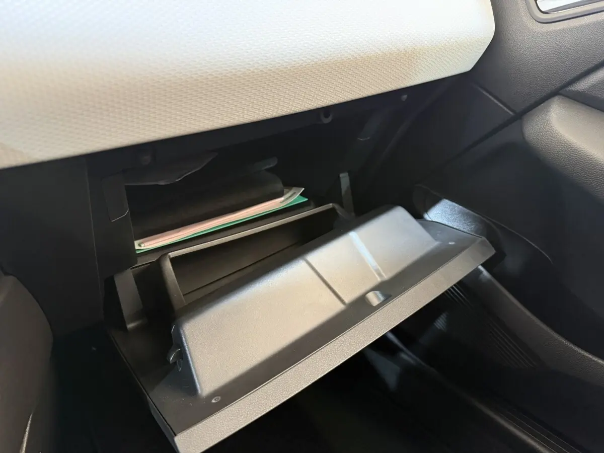 Gros plan sur la boîte à gants ouverte de la Renault Clio Business blanche, montrant l'intérieur et la planche de bord claire.