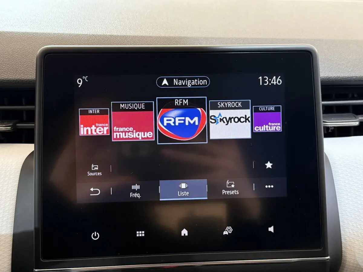 Écran tactile central de la Renault Clio Business blanc, affichant les stations radio avec interface moderne.