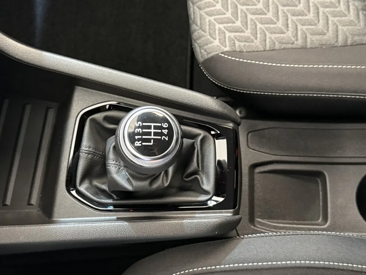 Gros plan sur levier de vitesses manuel noir dans Renault Clio Business blanc, avec sellerie grise et console centrale.