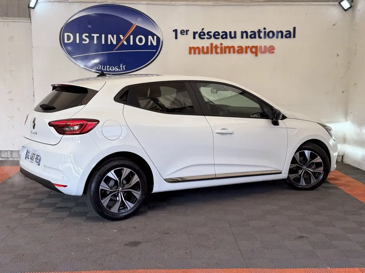 Profil droit d'une Renault Clio Business TCe 100 GPL blanche 2023 avec jantes alliage et toit spoiler noir.