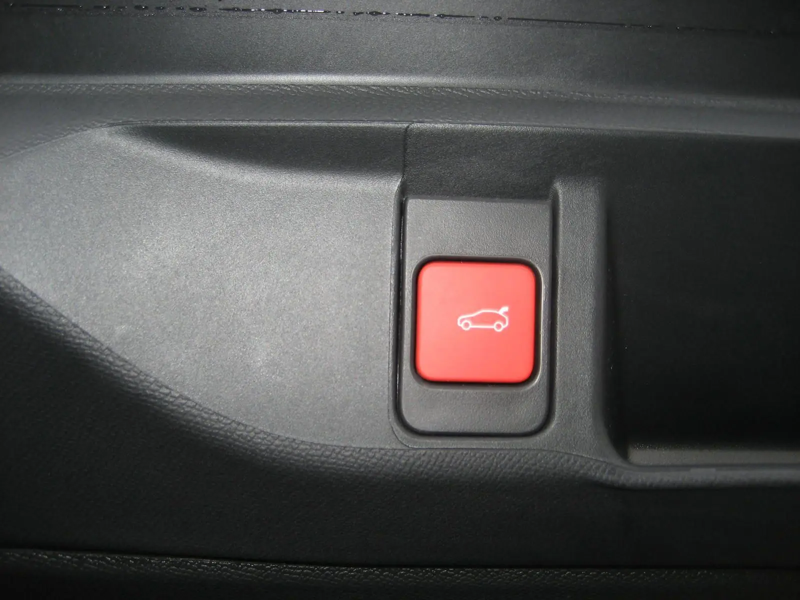 Bouton rouge de déverrouillage du coffre dans l'habitacle du DS4 II Pallas gris platinium 2024.