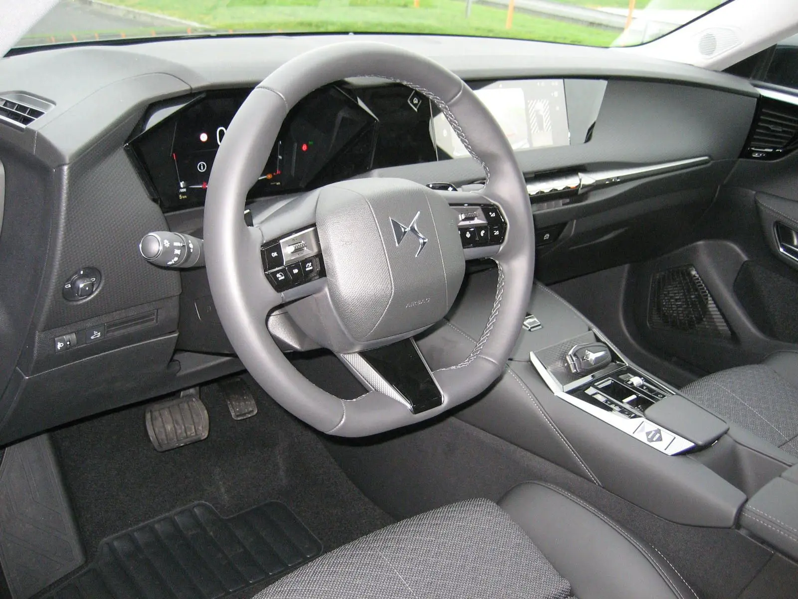 Intérieur du DS4 2024 en gris, vue côté conducteur sur le volant cuir et la console centrale moderne avec écran tactile.