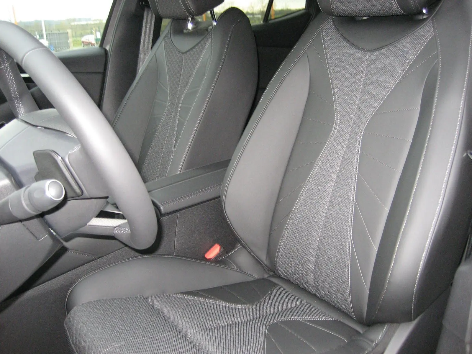 Gros plan sur les sièges avant en cuir et tissu gris du DS4 2024, avec volant partiellement visible côté gauche.