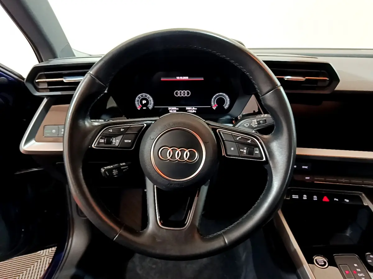 Vue centrée sur le volant cuir noir et le tableau de bord numérique de l'Audi A3 35 TFSI bleu 2023.