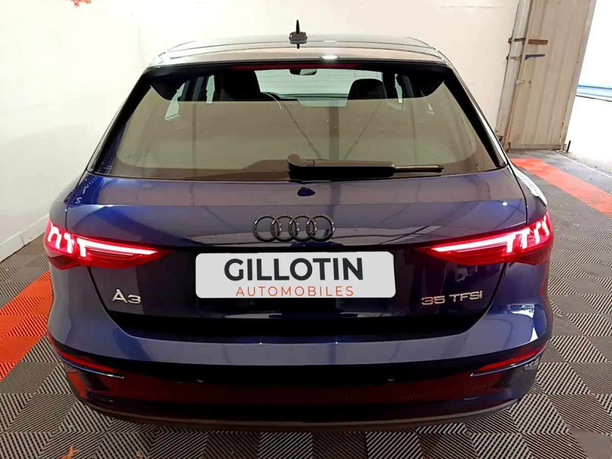 Vue arrière d'une Audi A3 35 TFSI bleu avec feux LED allumés dans un garage fermé.