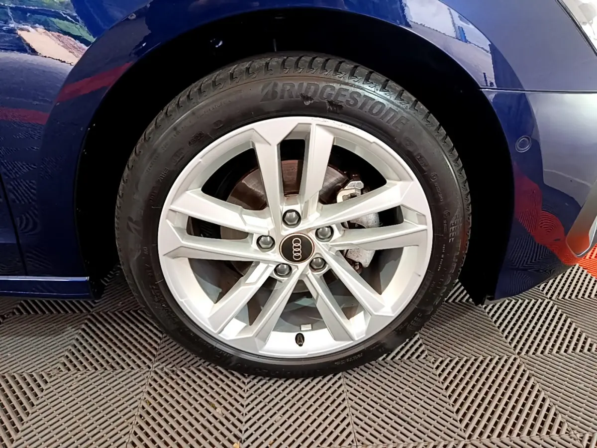 Gros plan sur la roue avant droite de l'Audi A3 bleu 35 TFSI 150 MHEV avec jante argentée et pneu Bridgestone.