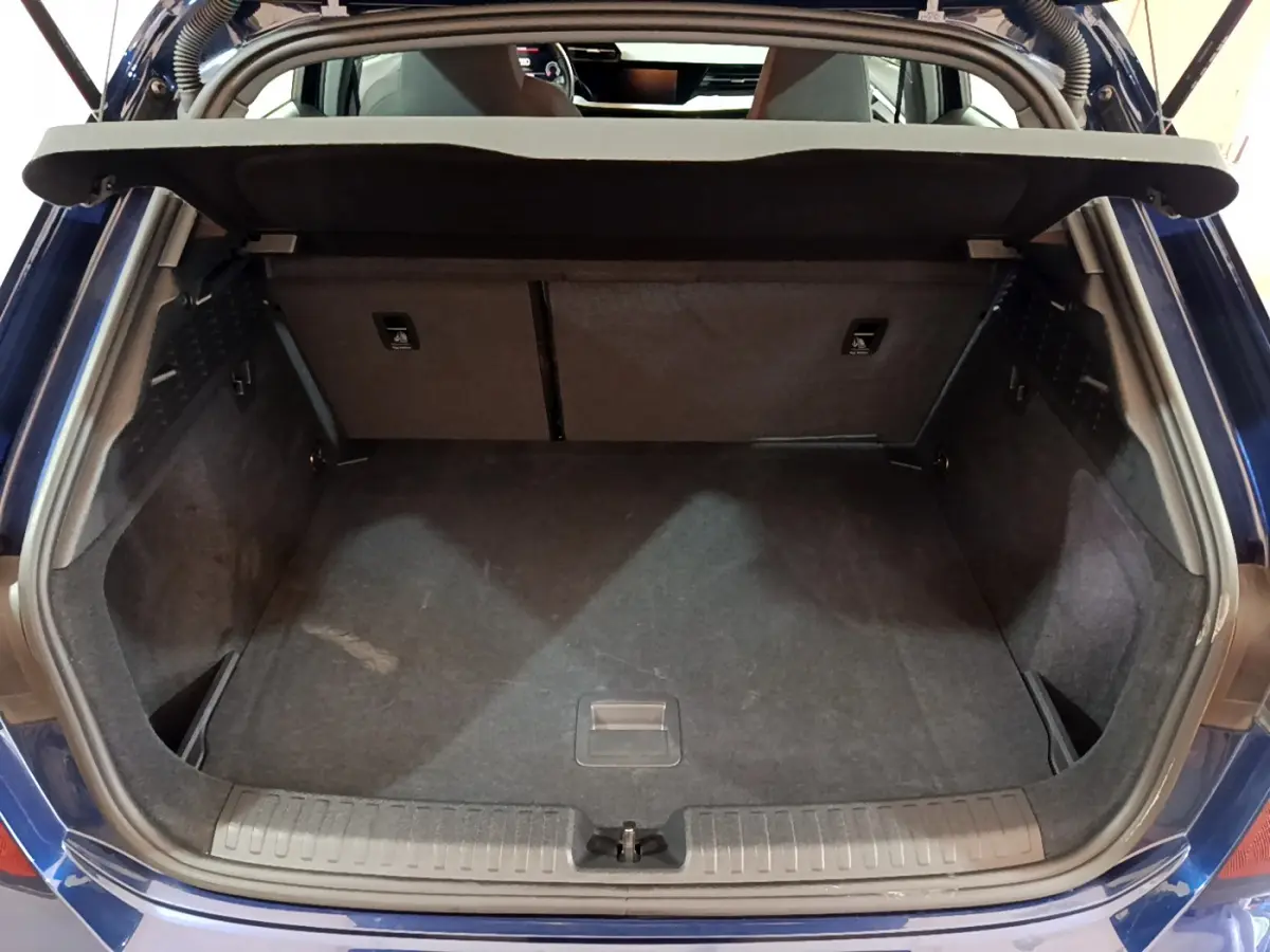Coffre ouvert vu de l'arrière d'une Audi A3 bleu 2023, montrant l'espace de chargement et la tablette de séparation.
