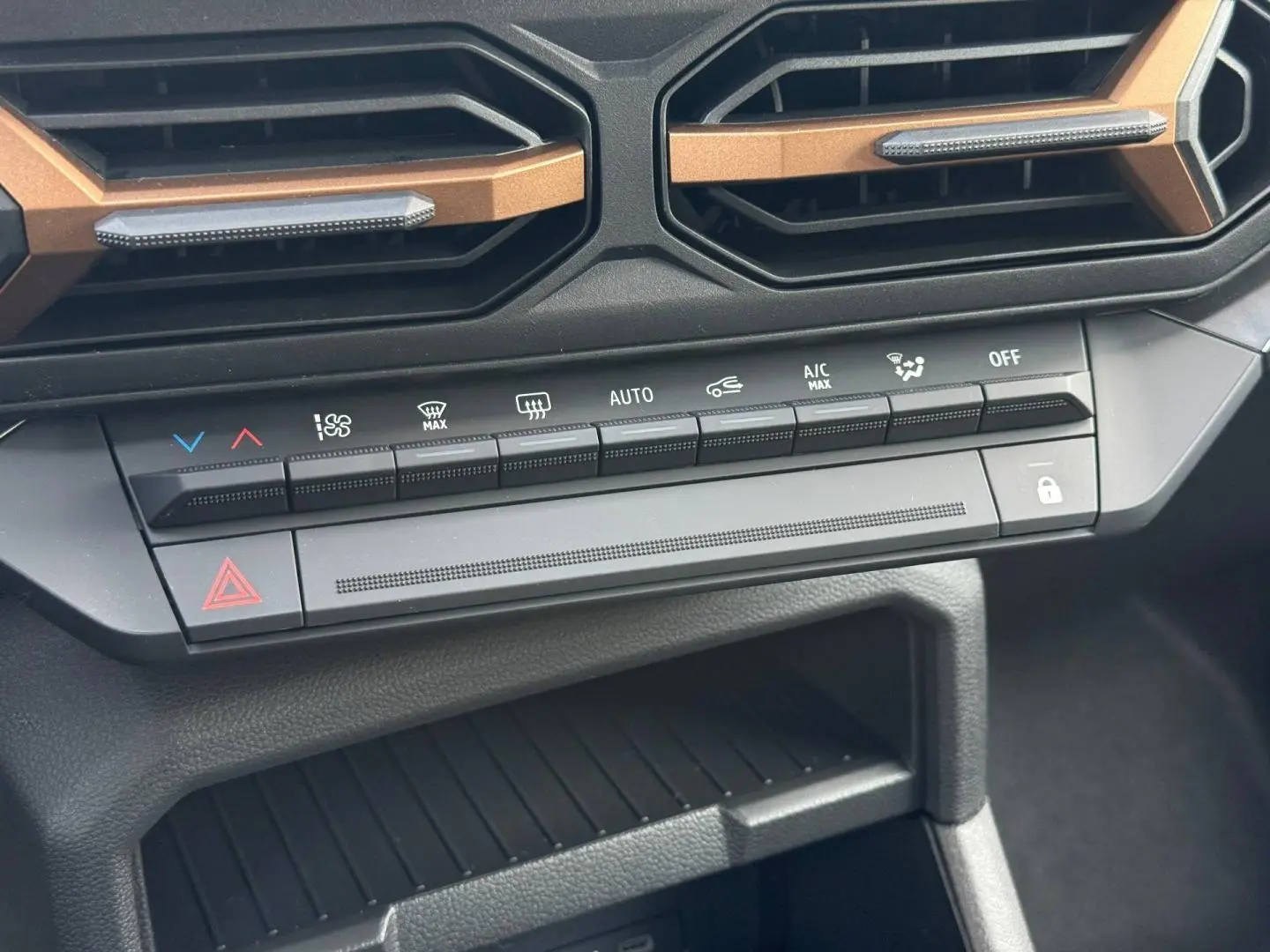 Détail du tableau de bord du Dacia Duster 2026 montrant les commandes de climatisation et les aérateurs avec inserts bronze.