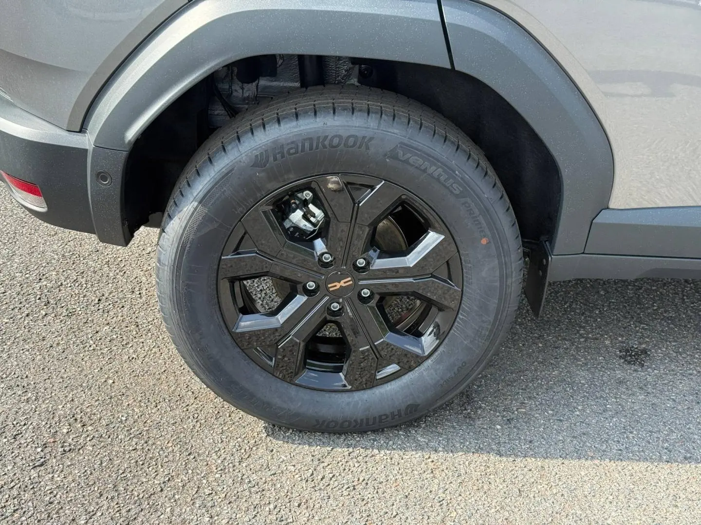 Gros plan sur la roue arrière droite du Dacia Duster gris 2026 avec jante alu noire et pneu Hankook.