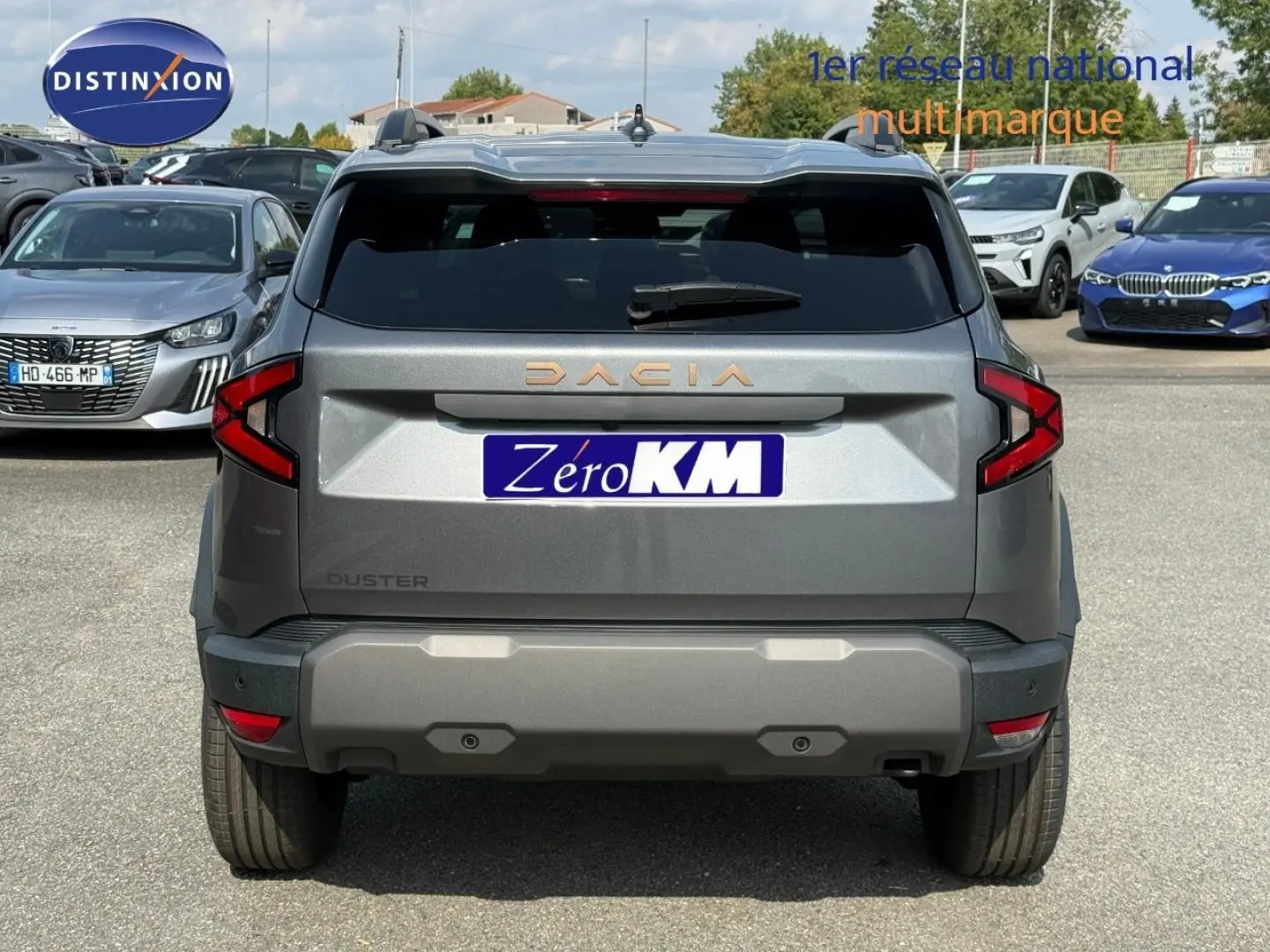 Vue arrière d'un Dacia Duster gris 2026 avec feux arrière en forme de C et logo DACIA en lettres dorées.