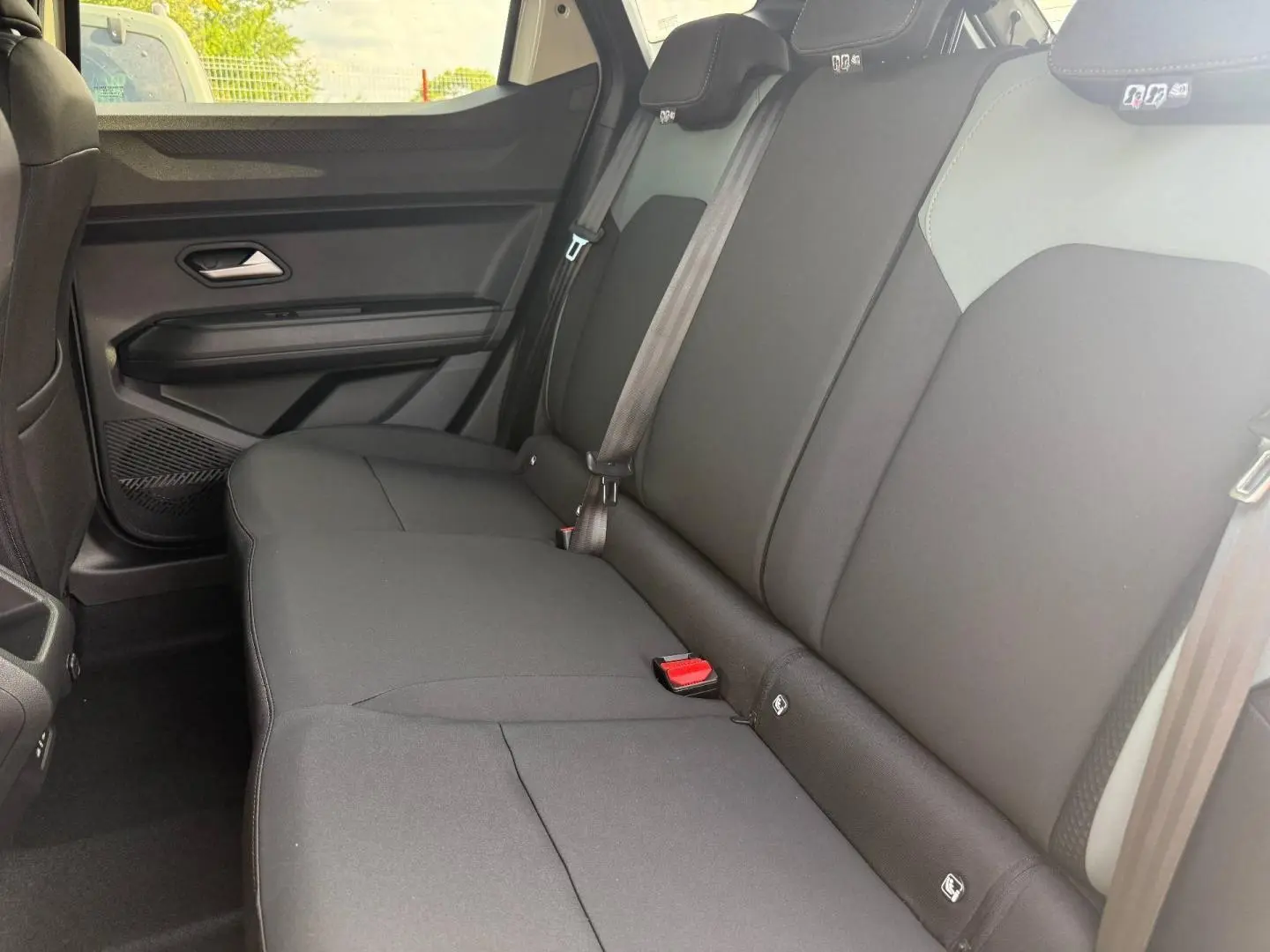 Vue latérale intérieure montrant la banquette arrière noire du Dacia Duster 2026 avec ceintures et appuie-têtes.