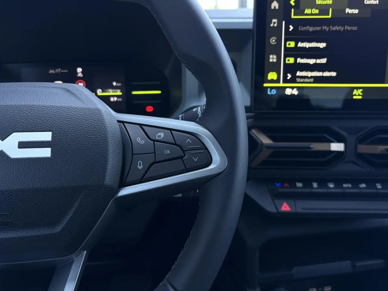 Gros plan sur le volant à droite et l’écran tactile central du tableau de bord du Dacia Duster blanc Glacier 2026.