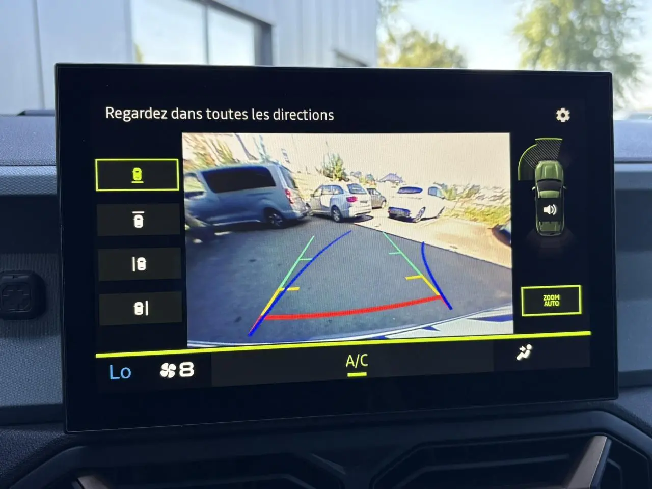 Écran tactile intérieur montrant la caméra multivues du Dacia Duster blanc Glacier en vue arrière pour le stationnement.
