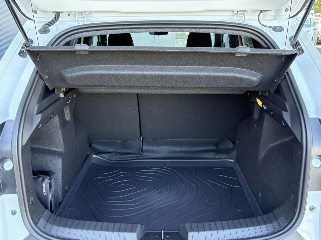 Coffre ouvert du Dacia Duster Blanc Glacier 2026, vue arrière montrant l'espace de chargement et la housse de protection.