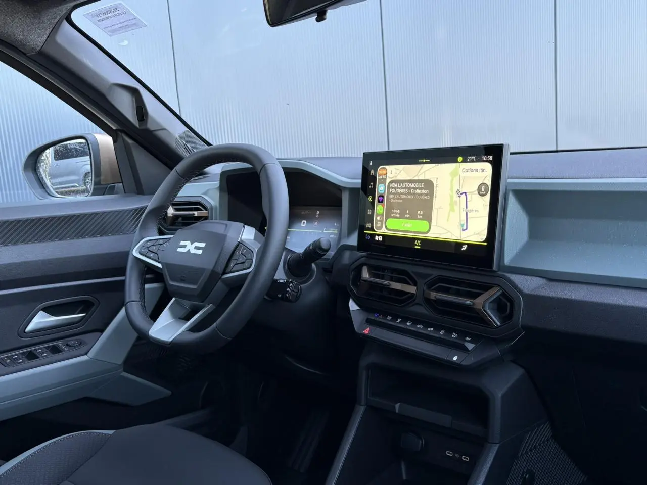 Vue intérieure côté conducteur du Dacia Duster 2026 blanc Glacier, avec tableau de bord digital et écran tactile central.