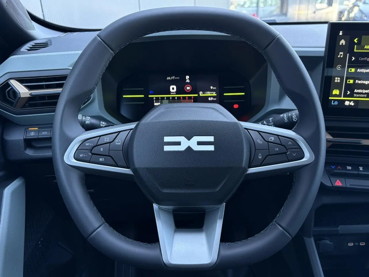 Vue centrée sur le volant noir du Dacia Duster 2026 avec tableau de bord digital et écran tactile latéral.