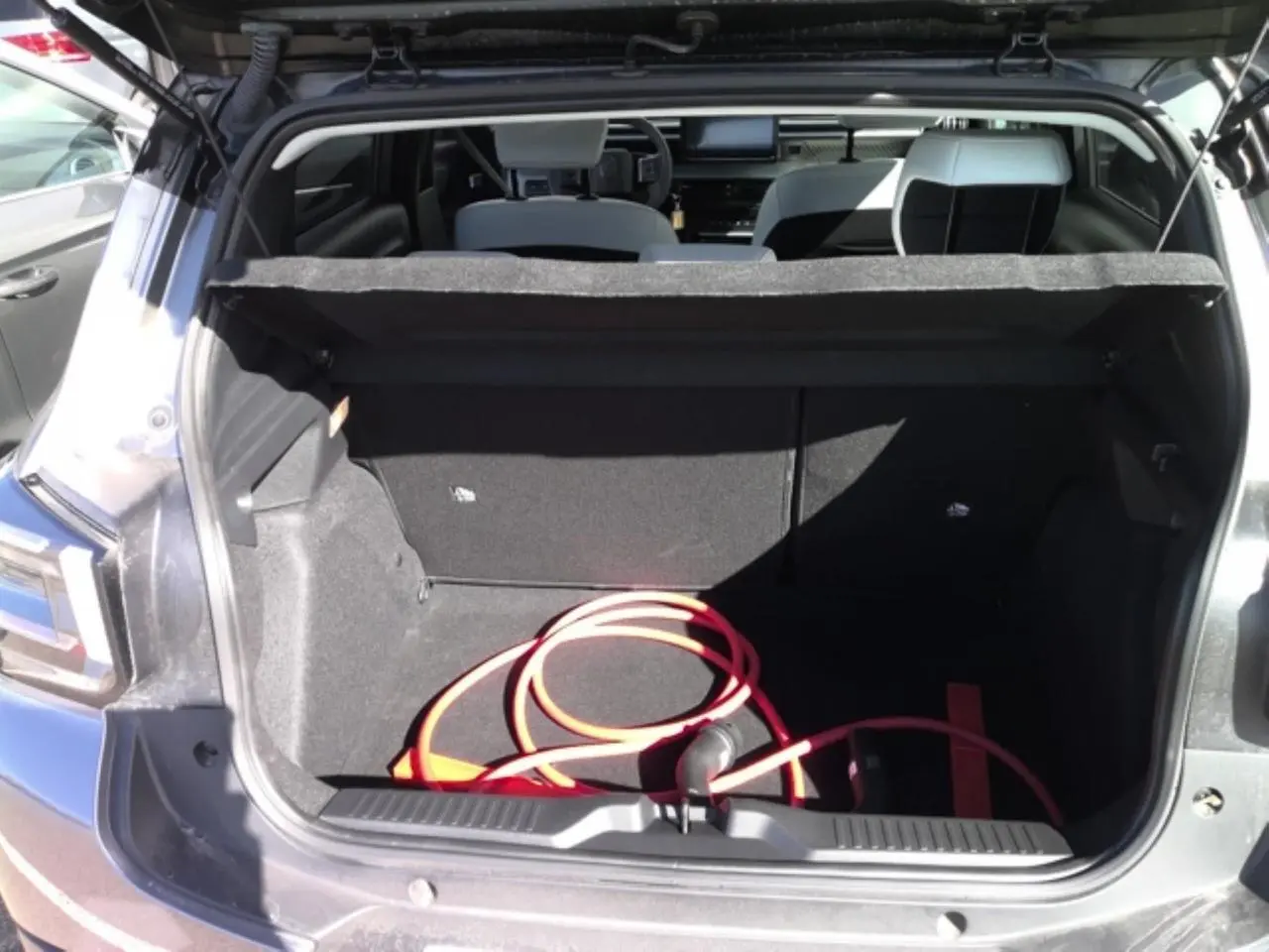 Coffre ouvert d’une Citroën C3 ë-113 Berline Max gris Artense 2025, avec câble de recharge électrique visible à l’intérieur.