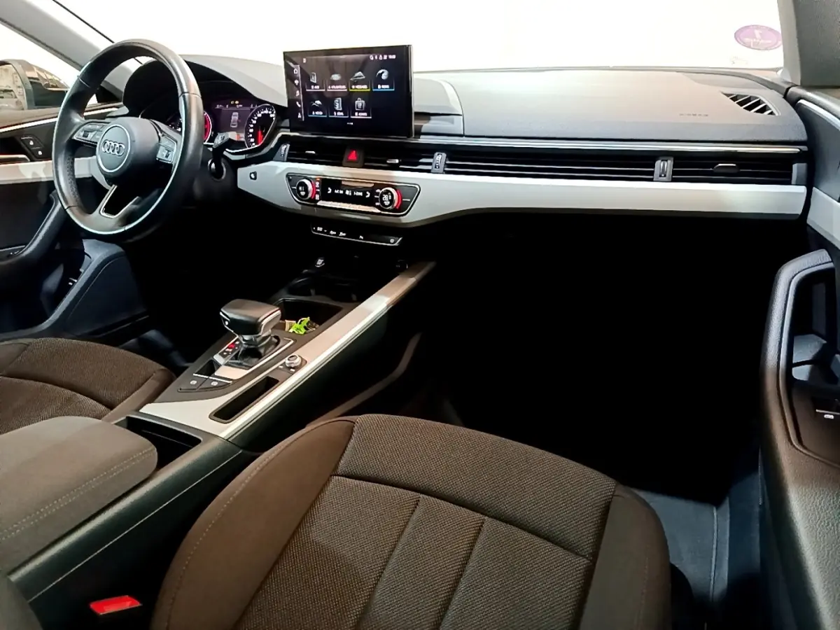 Intérieur Audi A5 2021 vu côté conducteur, tableau de bord noir avec écran central tactile et sièges tissu marron.