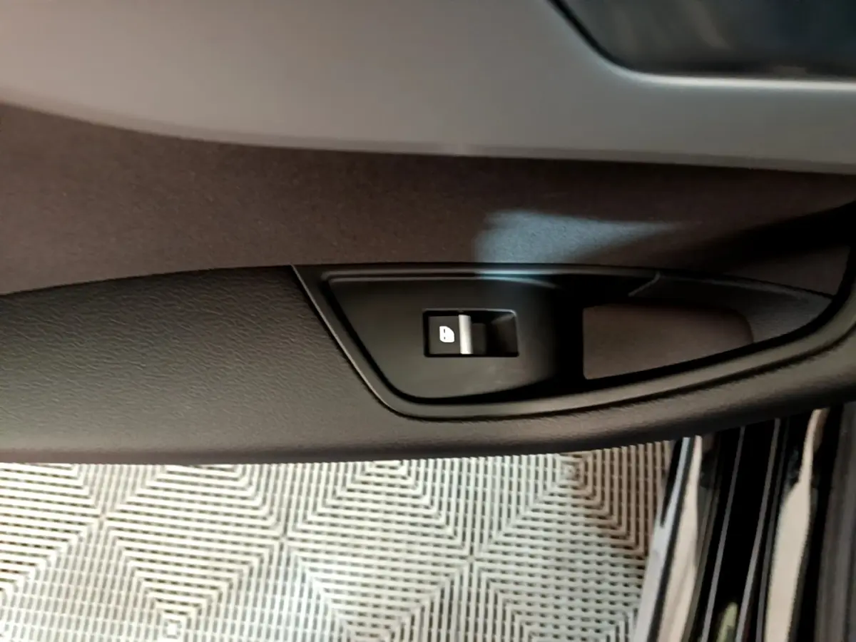 Gros plan sur le bouton de verrouillage de porte côté conducteur d'une Audi A5 noire, intérieur visible.