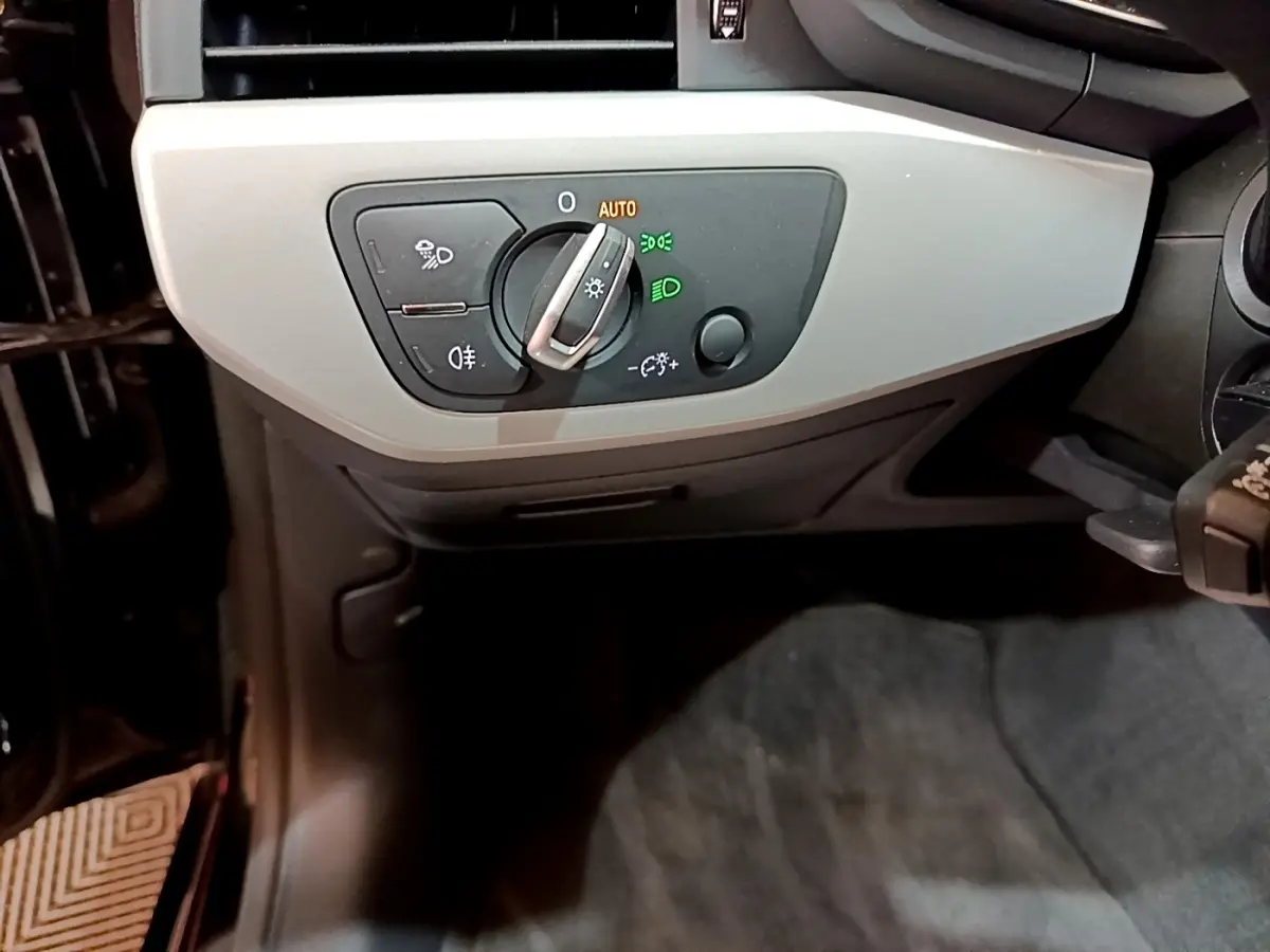 Gros plan sur le panneau de commande des phares à gauche du volant dans l'Audi A5 35 TFSI noire de 2021.