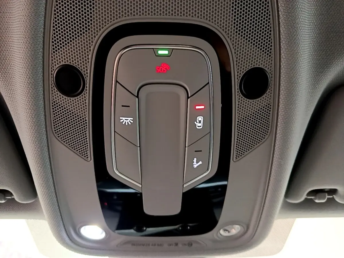 Vue en gros plan du panneau de commandes au plafond intérieur de l'Audi A5 noir, avec bouton SOS et éclairage intégré.
