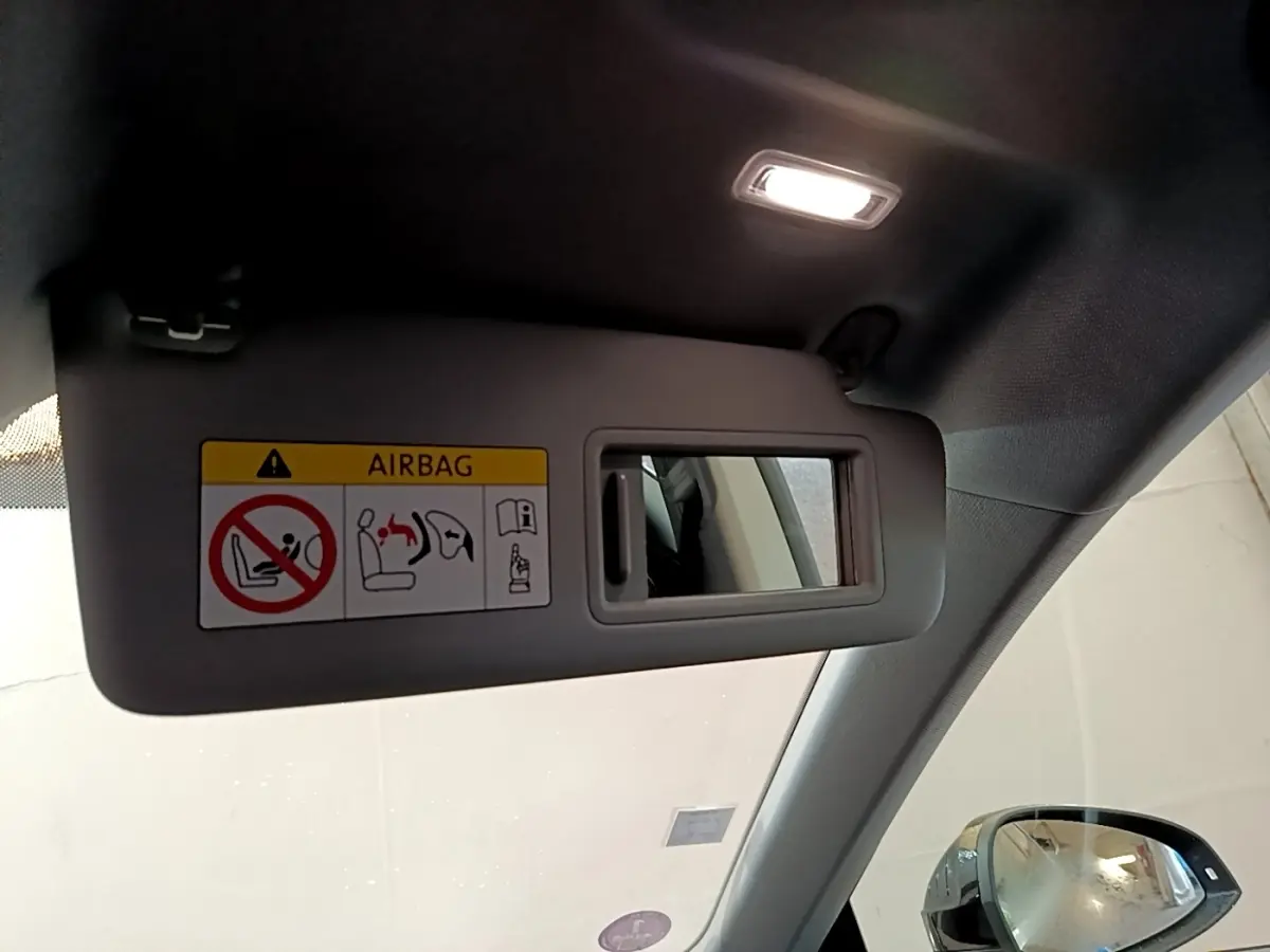 Détail du pare-soleil côté conducteur avec miroir et avertissement airbag dans l'Audi A5 noire de 2021.
