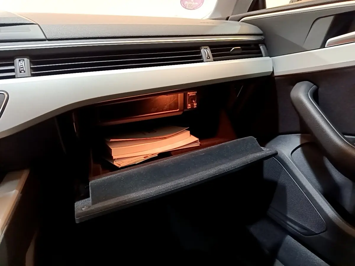 Intérieur de l'Audi A5 35 TFSI 2021, vue du côté passager sur la boîte à gants ouverte avec documents visibles.