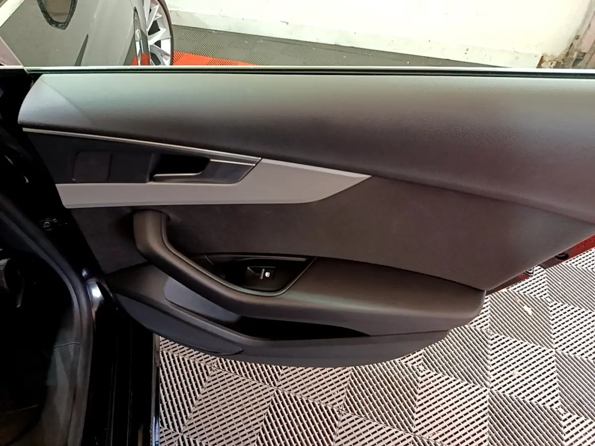 Porte intérieure côté gauche noire de l'Audi A5 35 TFSI 2021 avec poignée argentée et commande de vitre électrique.