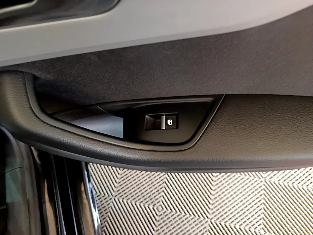 Bouton de verrouillage centralisé sur la portière côté gauche d'une Audi A5 noire, vue en gros plan intérieur.