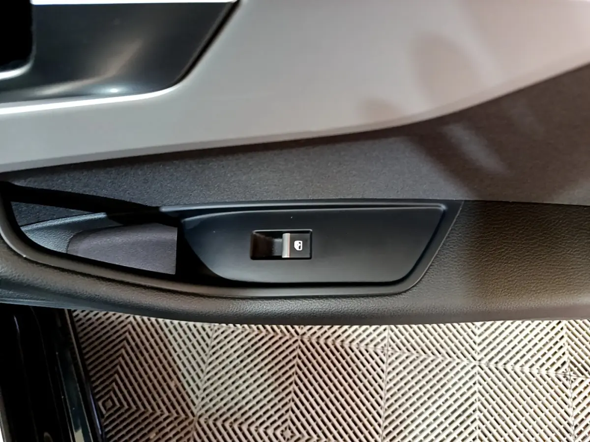 Bouton de verrouillage des portes sur la portière côté gauche d'une Audi A5 noire, vue en gros plan intérieur.