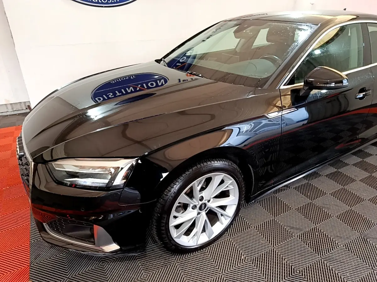 Audi A5 noir vue 3/4 avant droit, mettant en valeur ses jantes argentées et ses phares LED modernes.