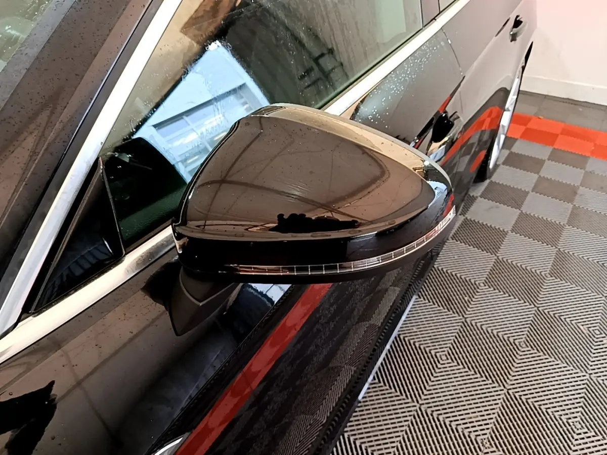 Rétroviseur côté gauche noir brillant de l'Audi A5 35 TFSI 2021, vue rapprochée avec reflet et gouttes d'eau.