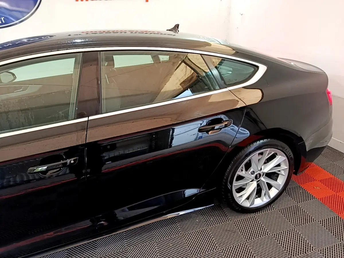 Profil côté gauche de l'Audi A5 noire 2021 avec jantes alliage et ligne de toit sportive dans un garage.