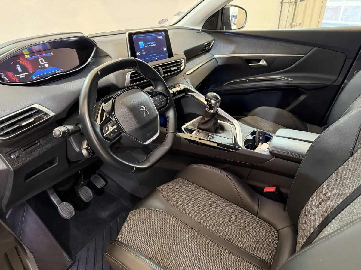 Vue intérieure côté conducteur du Peugeot 5008 avec volant cuir multifonctions et levier de vitesse manuel.