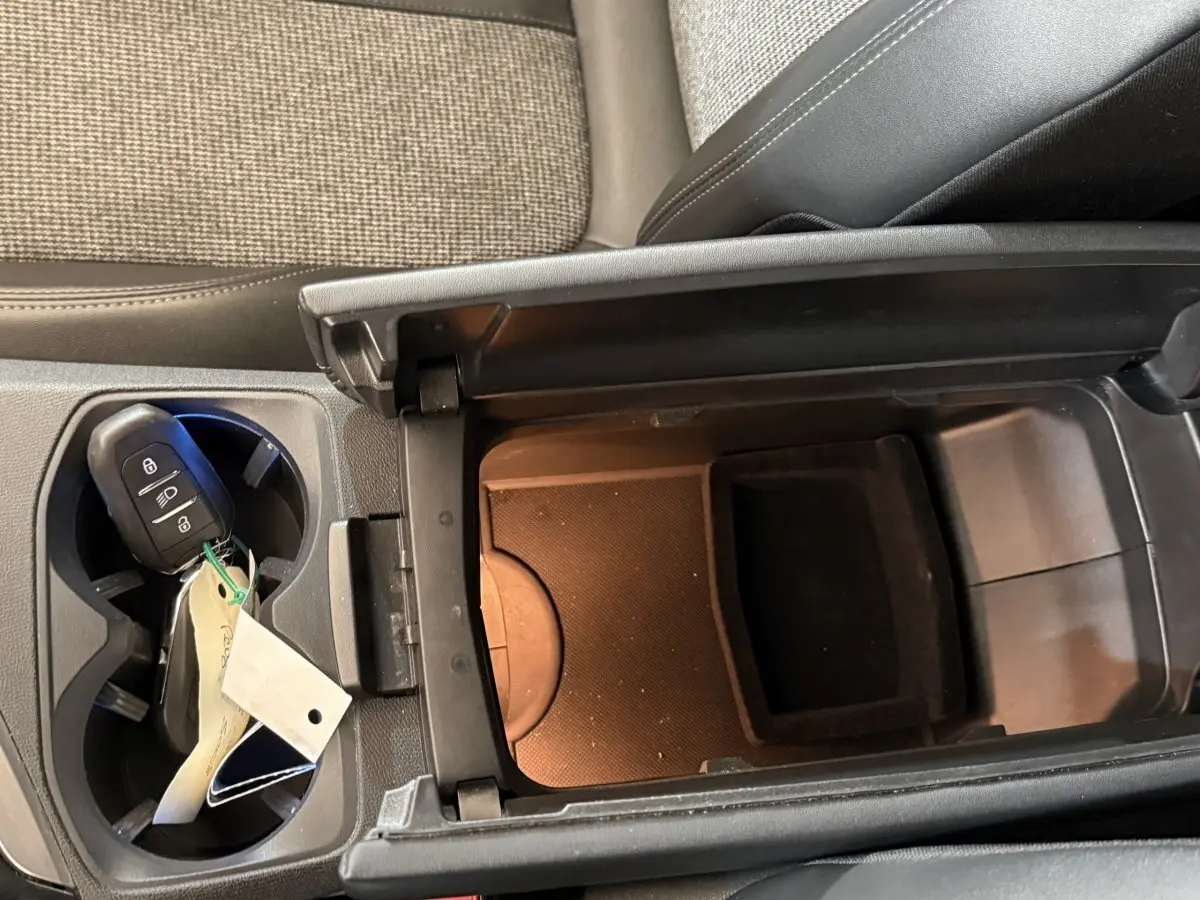 Vue rapprochée de la console centrale intérieure du Peugeot 5008 2019, avec accoudoir ouvert et clé dans porte-gobelets.