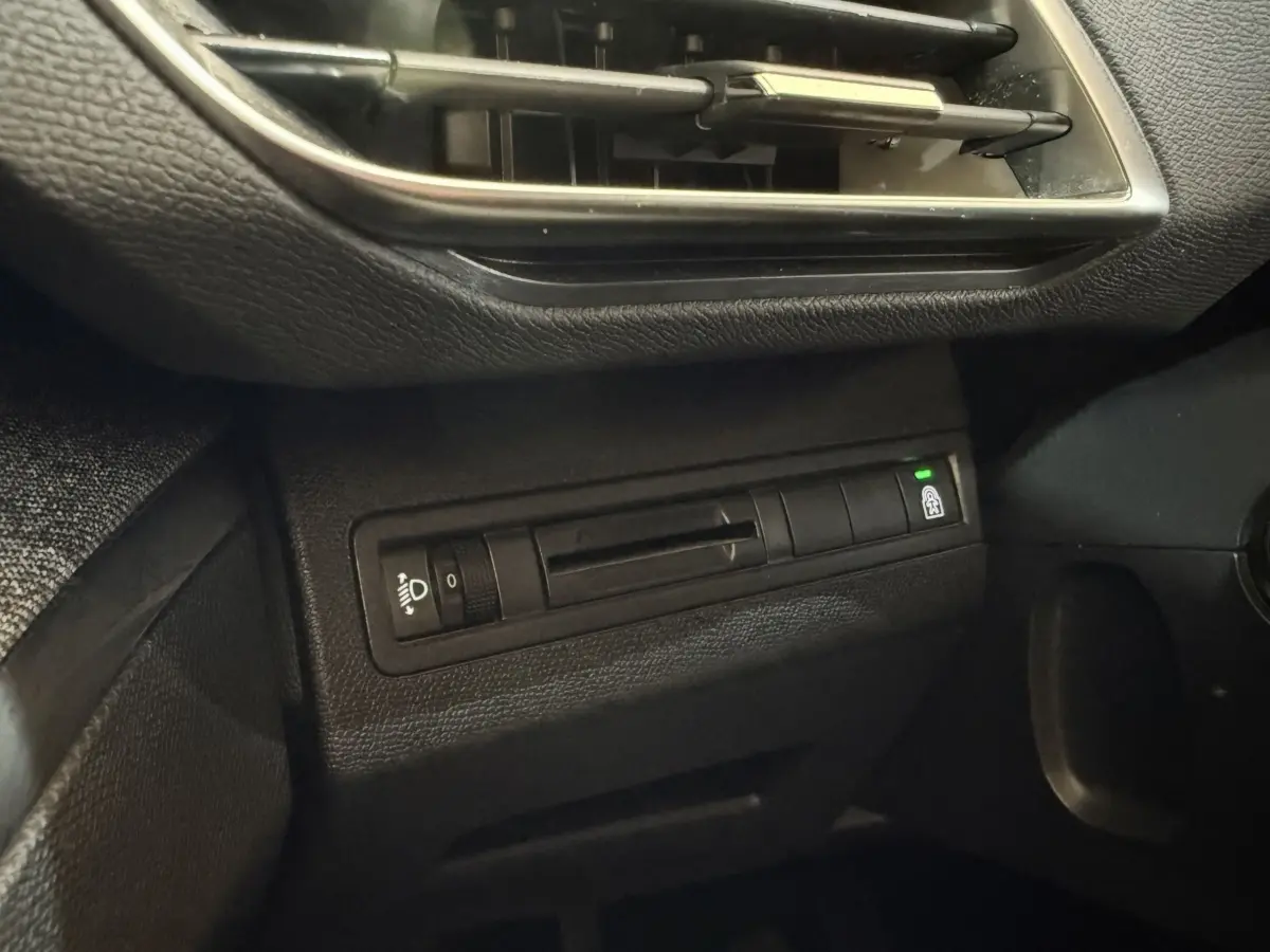 Détail du tableau de bord noir du Peugeot 5008 2019 avec commande réglage phares et bouton verrouillage portes.