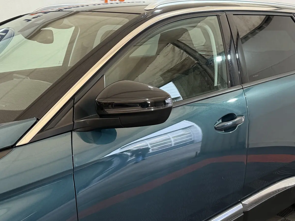 Vue côté gauche rapprochée du Peugeot 5008 bleu avec rétroviseur noir brillant et contours chromés.