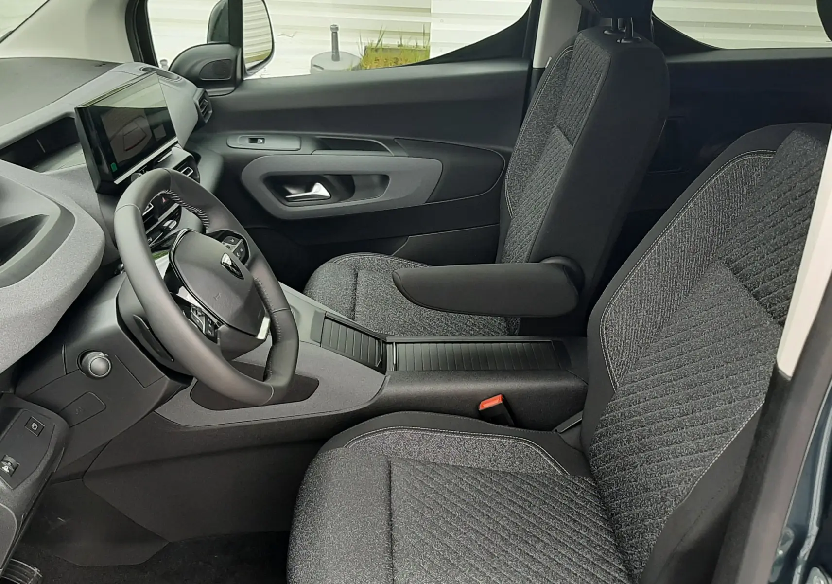 Vue intérieure côté conducteur du Peugeot Rifter Bleu Kiama 2026, montrant les sièges tissu gris et le tableau de bord moderne.