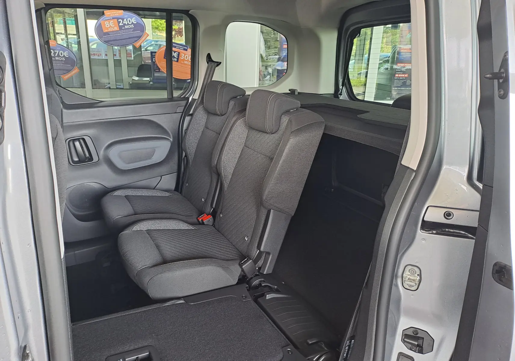 Vue intérieure côté droit du Peugeot Rifter 2026 bleu Kiama, montrant les sièges arrière en tissu gris foncé.