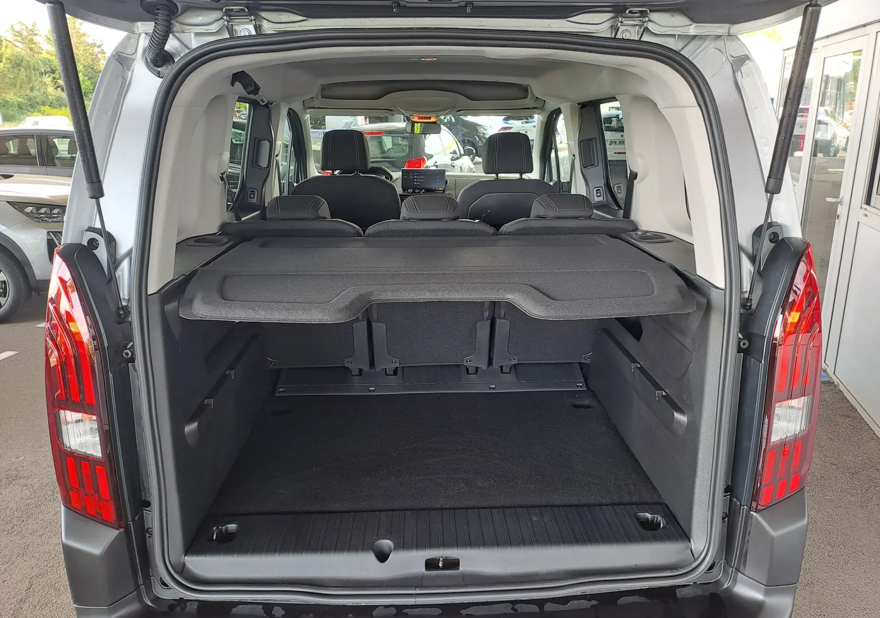Vue arrière ouverte du coffre du Peugeot Rifter bleu Kiama, montrant l’espace de chargement et les sièges arrière rabattus.