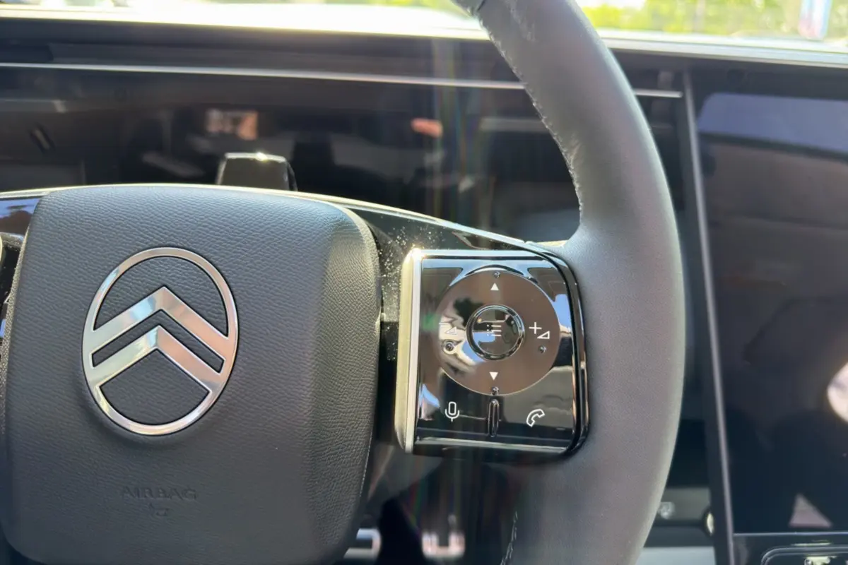 Gros plan sur le volant cuir du Citroën C5 Aircross gris platinium, avec commandes multifonctions et logo central chrome.