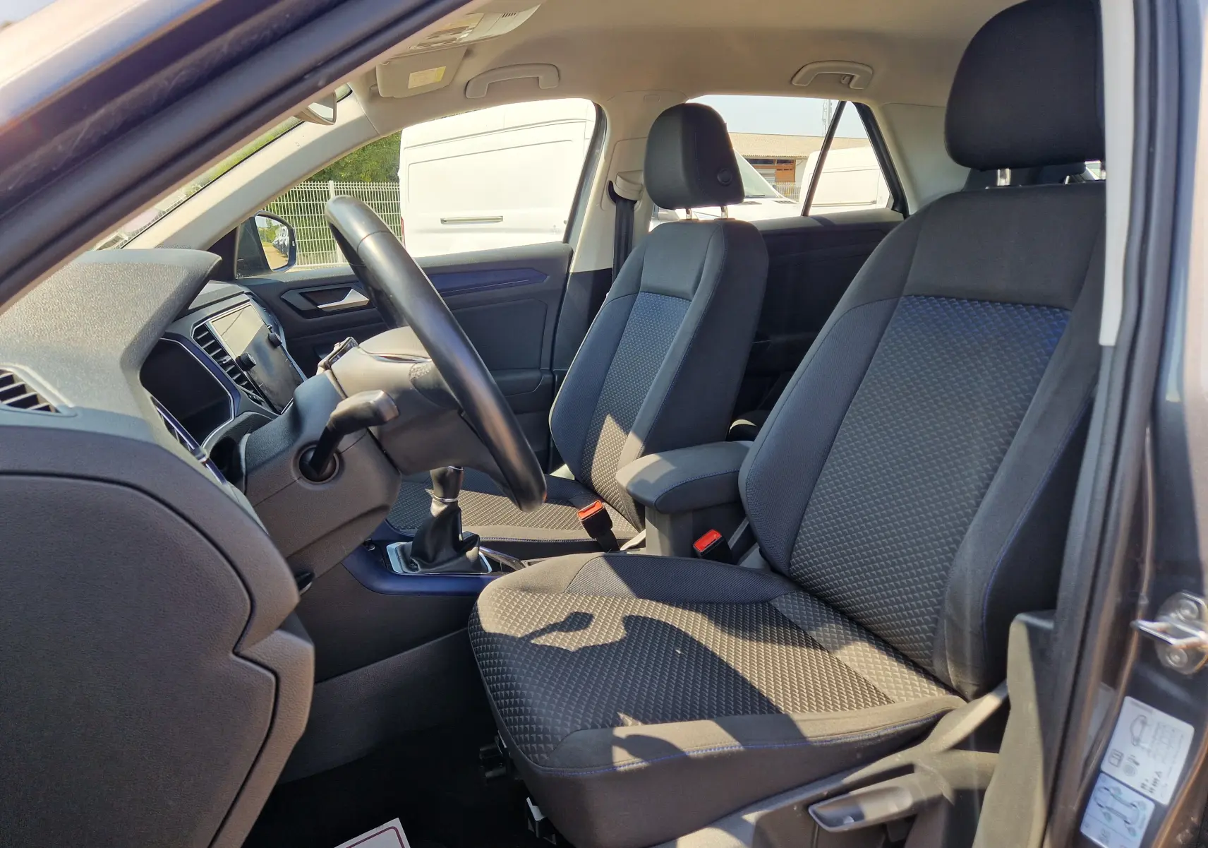 Vue intérieure côté conducteur du Volkswagen T-Roc gris foncé métal 2021, montrant les sièges avant et le volant.
