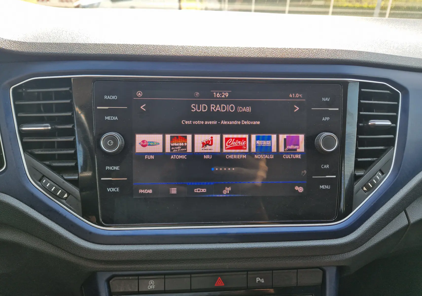 Écran tactile central du Volkswagen T-Roc 1.0 TSI 115 United 2021, affichant les stations radio, entouré de commandes noires.