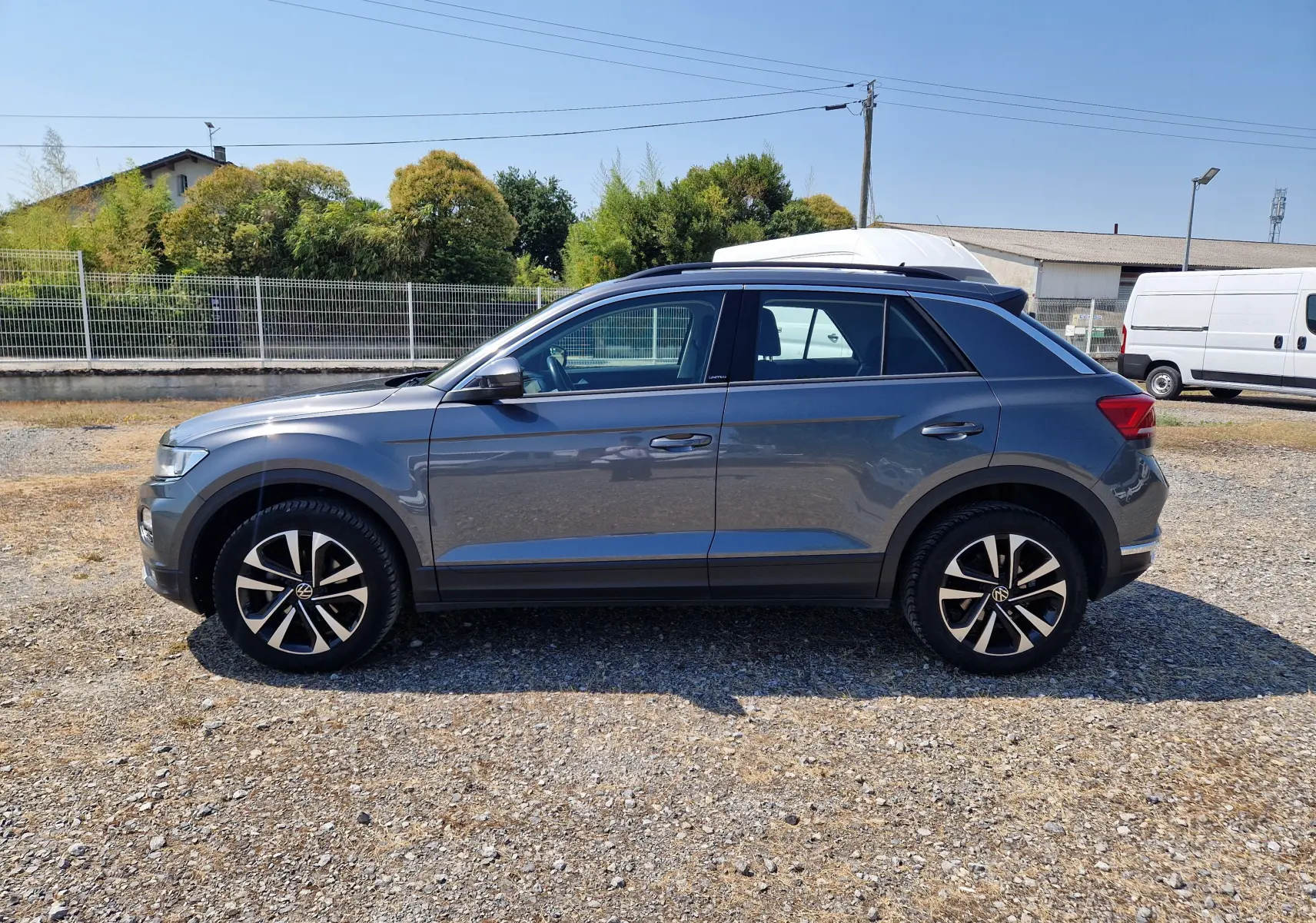 Volkswagen T-Roc gris foncé métal vu de profil côté gauche, avec jantes alliage noires et toit noir contrasté.