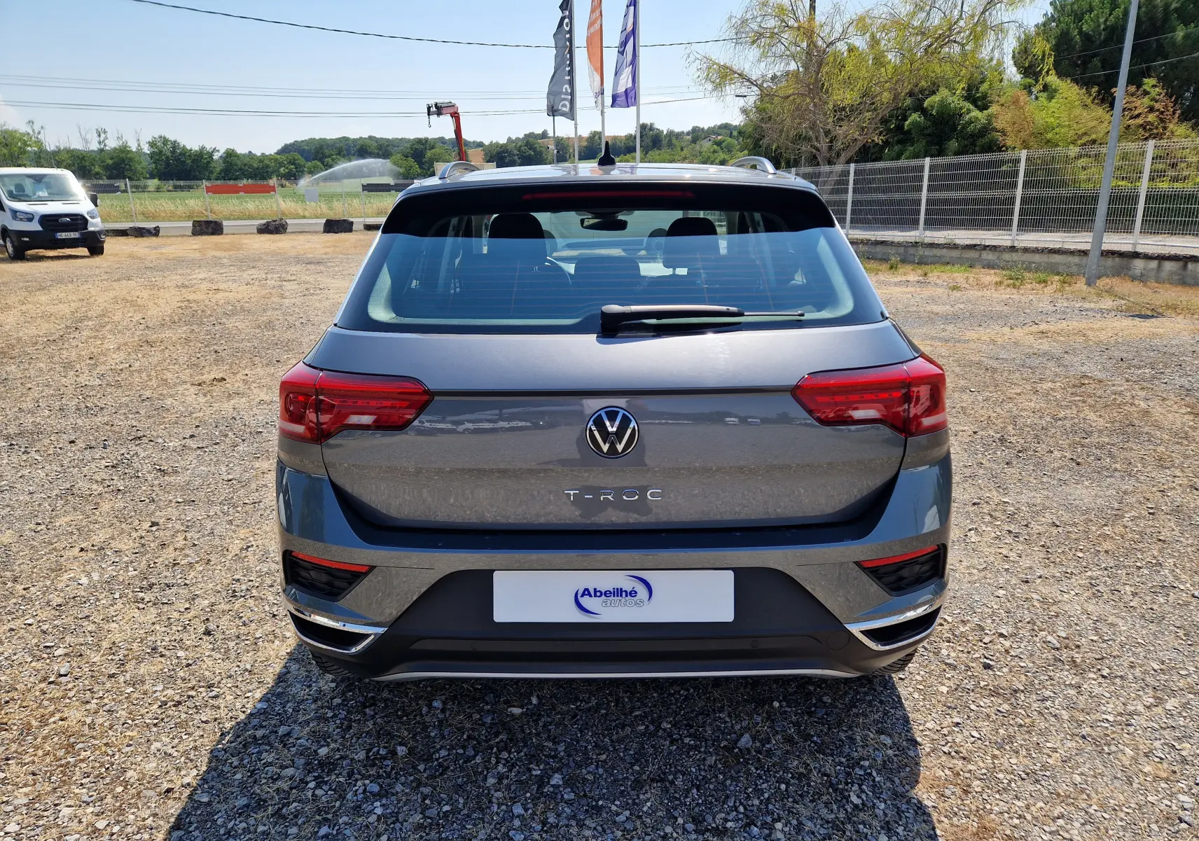 Vue arrière d’un Volkswagen T-Roc gris foncé métal 2021, avec feux arrière rouges et logo VW bien visible.