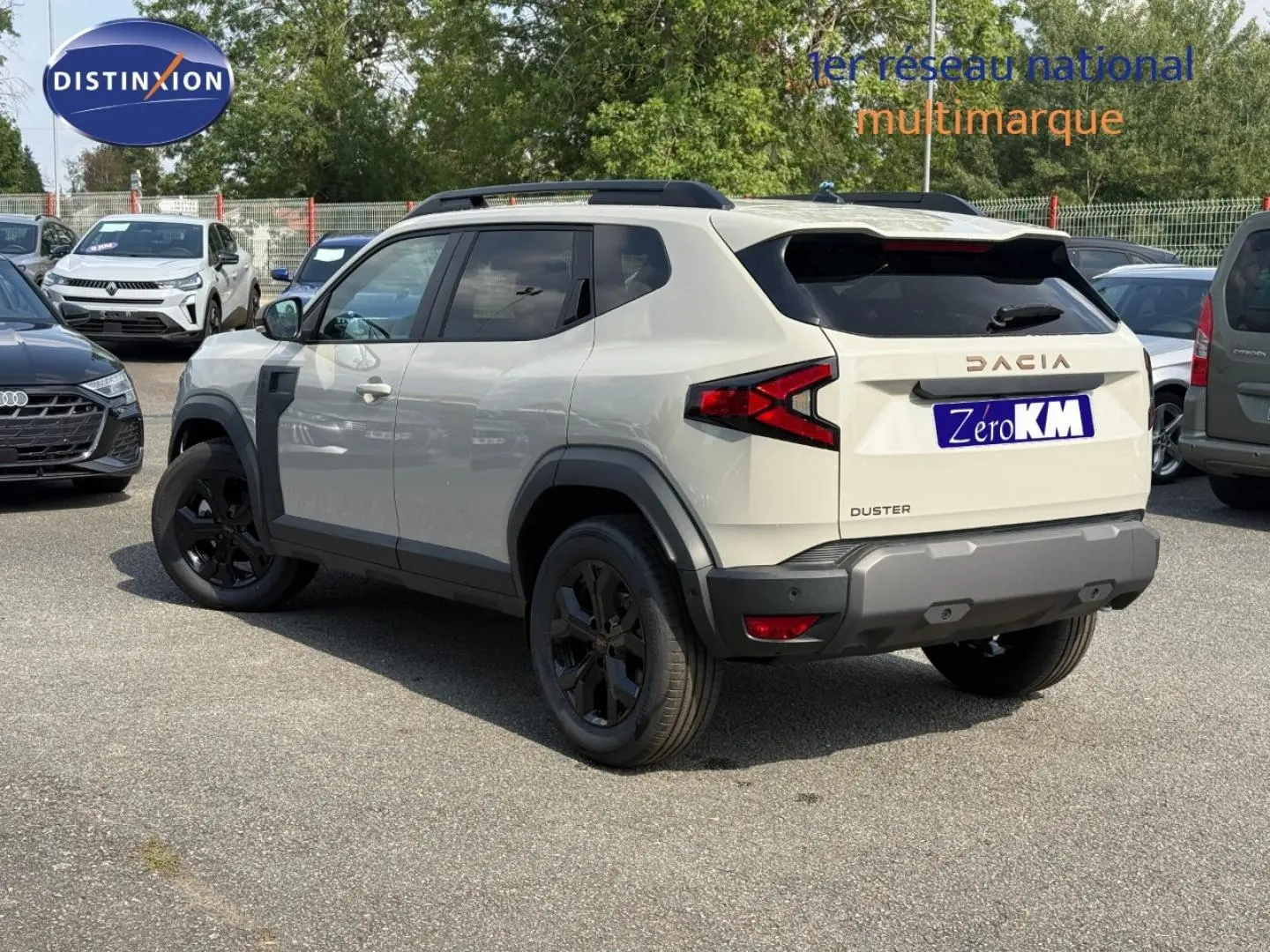 Vue 3/4 arrière droite d'un Dacia Duster blanc Glacier avec jantes noires et barres de toit noires.
