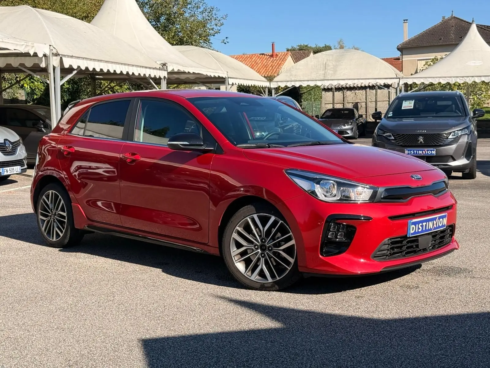 KIA RIO rouge grenadine vue 3/4 avant droit, avec jantes alliage et calandre noire distinctive.